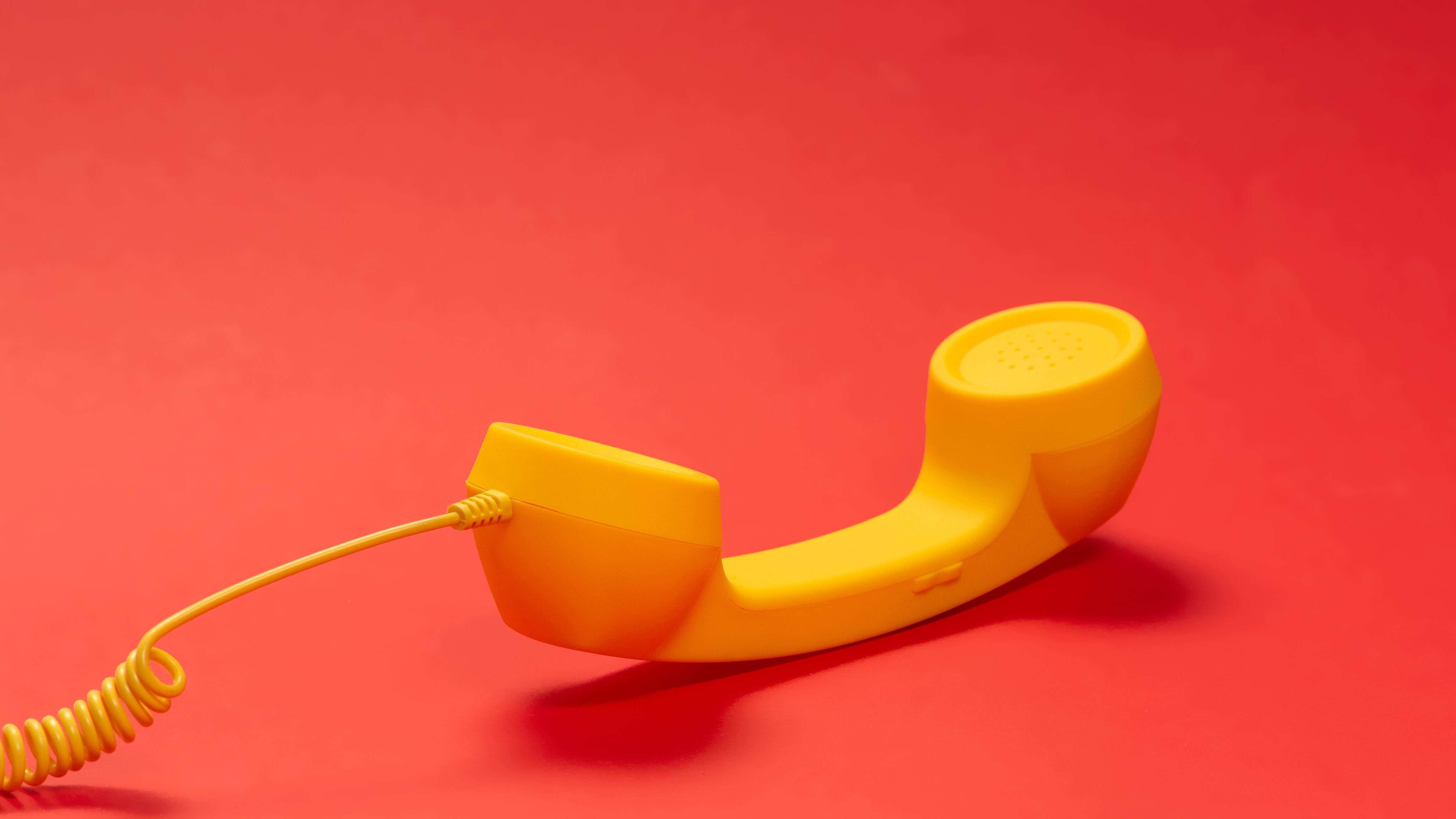 Yellow phone handset on red background.